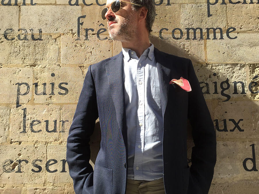 homme portant des lunettes de soleil et une pochette en soie rose dans le poche de sa veste