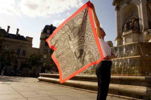 woman holding arabesque scarf with pink boarder by the fountain