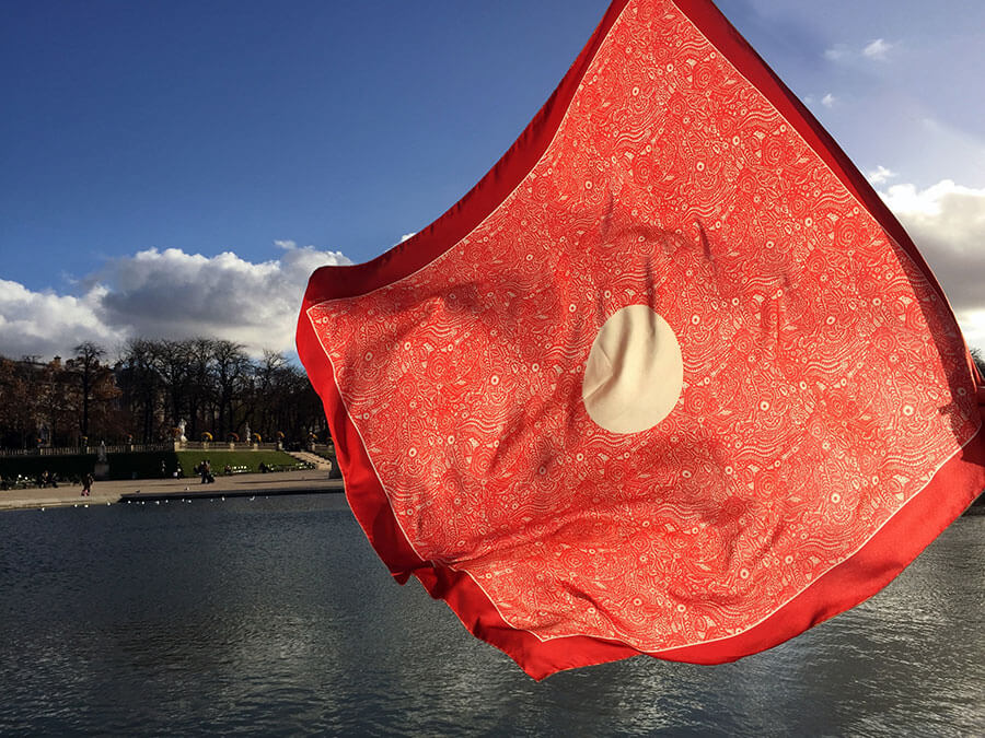 red silk scarf with circle against blue water and sky