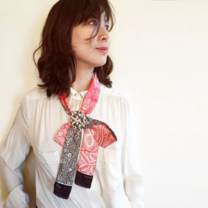 woman with pink and grey arabesque skinny silk scarf in a bow