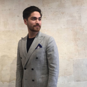 man with grey arabesque silk pocket square with navy boarder.