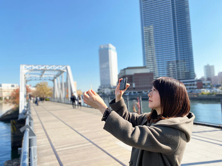 artiste japonaise debout sur un pont avec des gratte-ciels en arrière plan