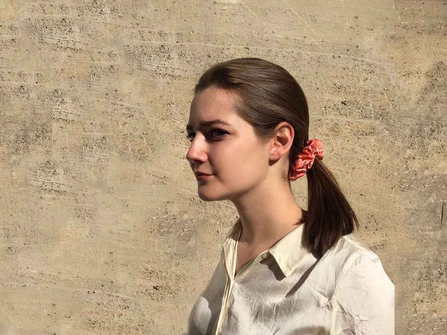 parisian lady wearing white shirt with a red hairscrunchy around her hair