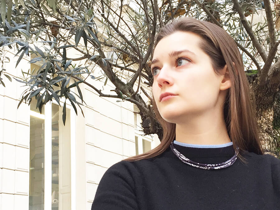 young lady wearing printed blue silk necklace with tree behind