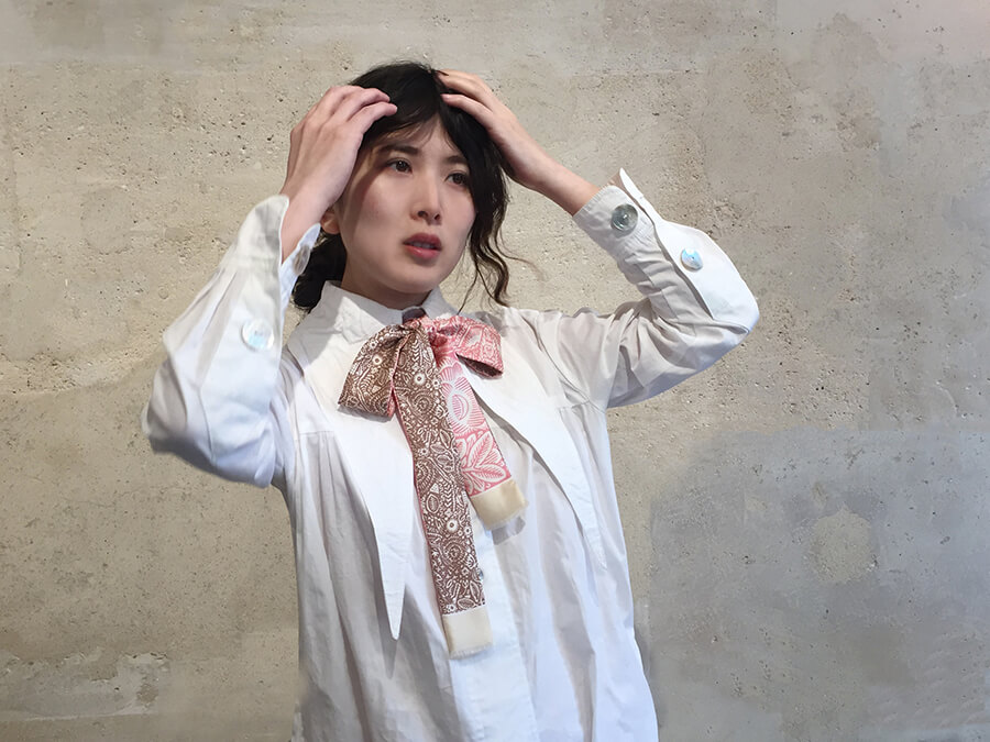 asian lady wearing white shirt with a long silk scarf, rose and black, tied around her neck