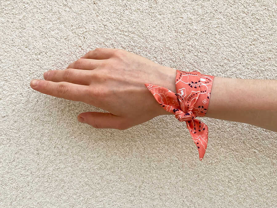 rose bandana printed silk wristband tied around a wrist with wall behind