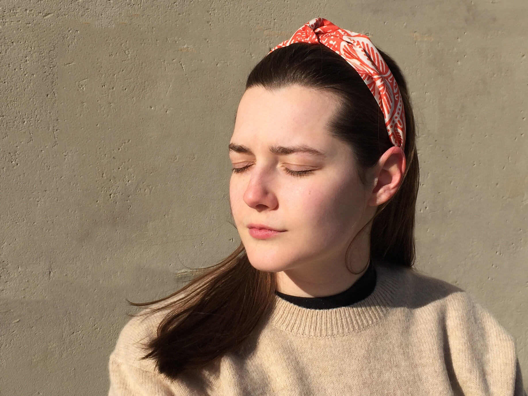 young lady wearing beige sweat shirt wearing a colourful hairband in her hair