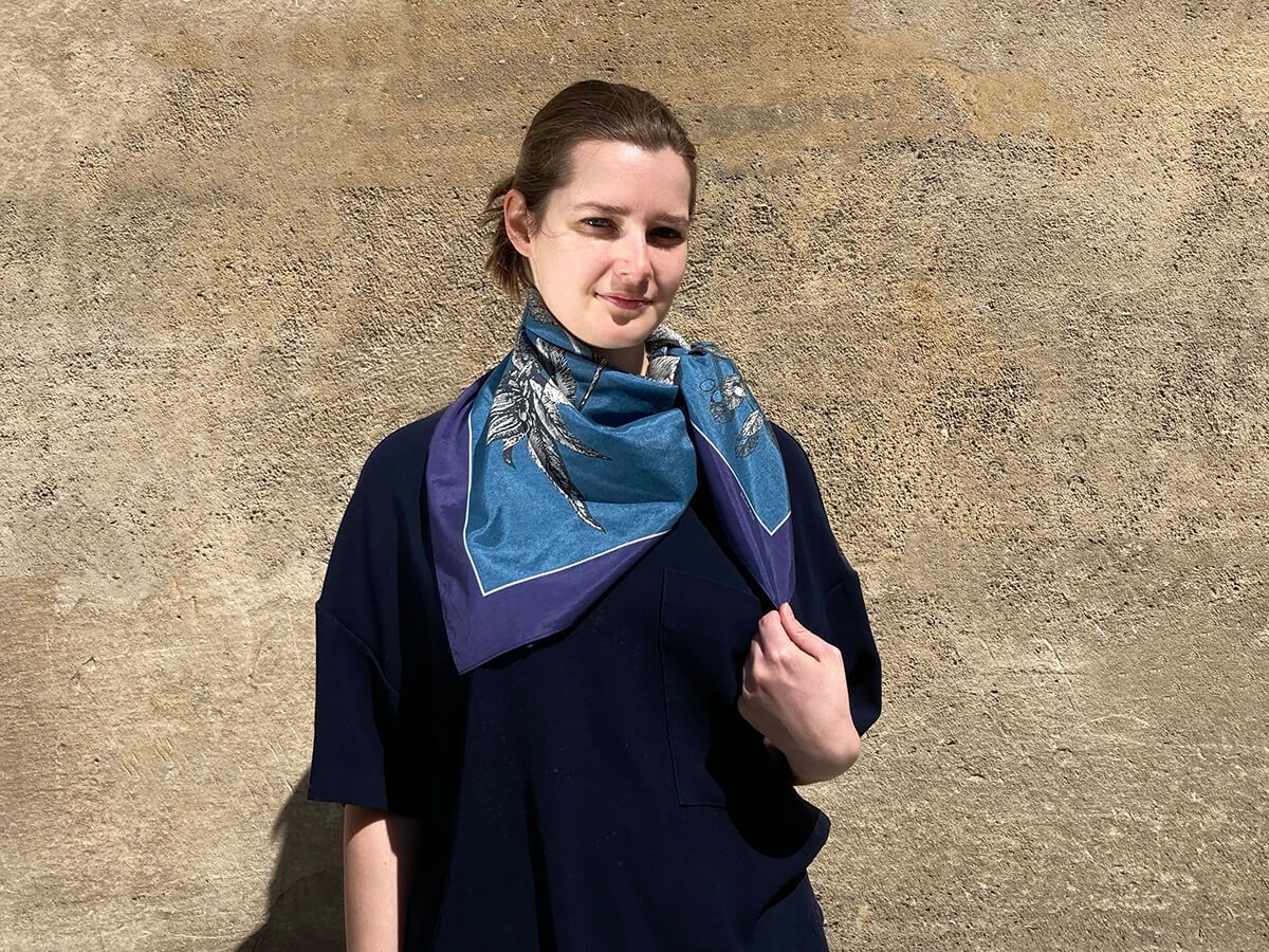 young lady wearing a black sweat shirt and a blue and black silk scarf with flower motif