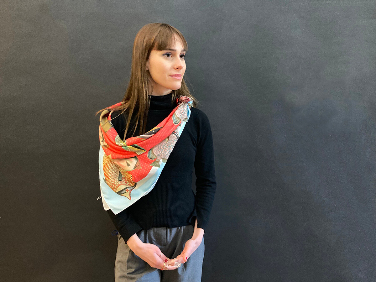 young lady wearing jean, a black sweat shirt and a silk scarf with fish motif