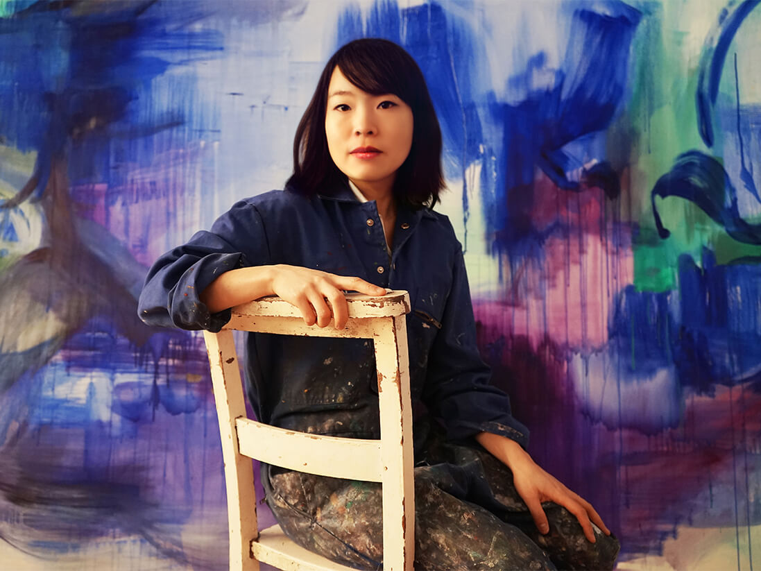 asian artist with colorful painting in the background