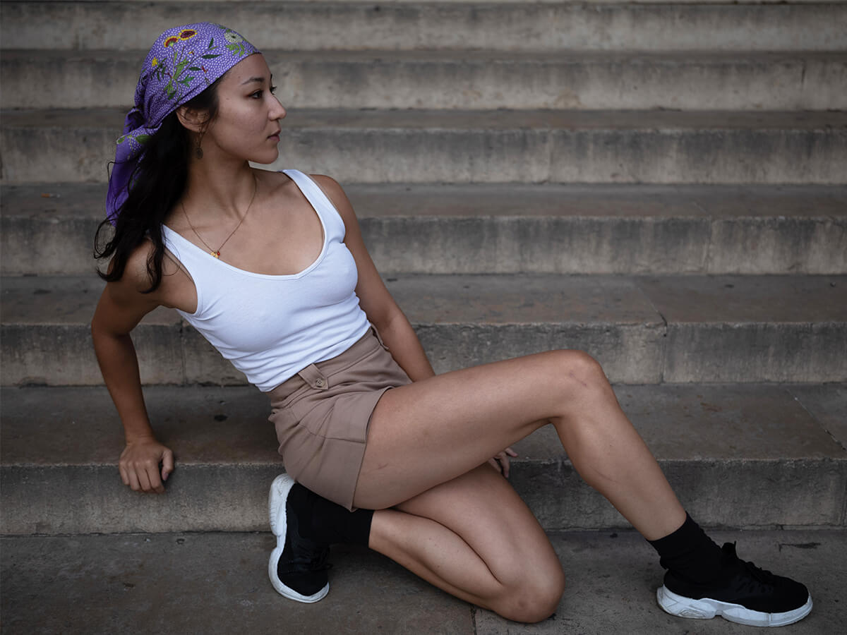 young lady wearing a purple silk scarf with flower motif around her head and a white t-shirt