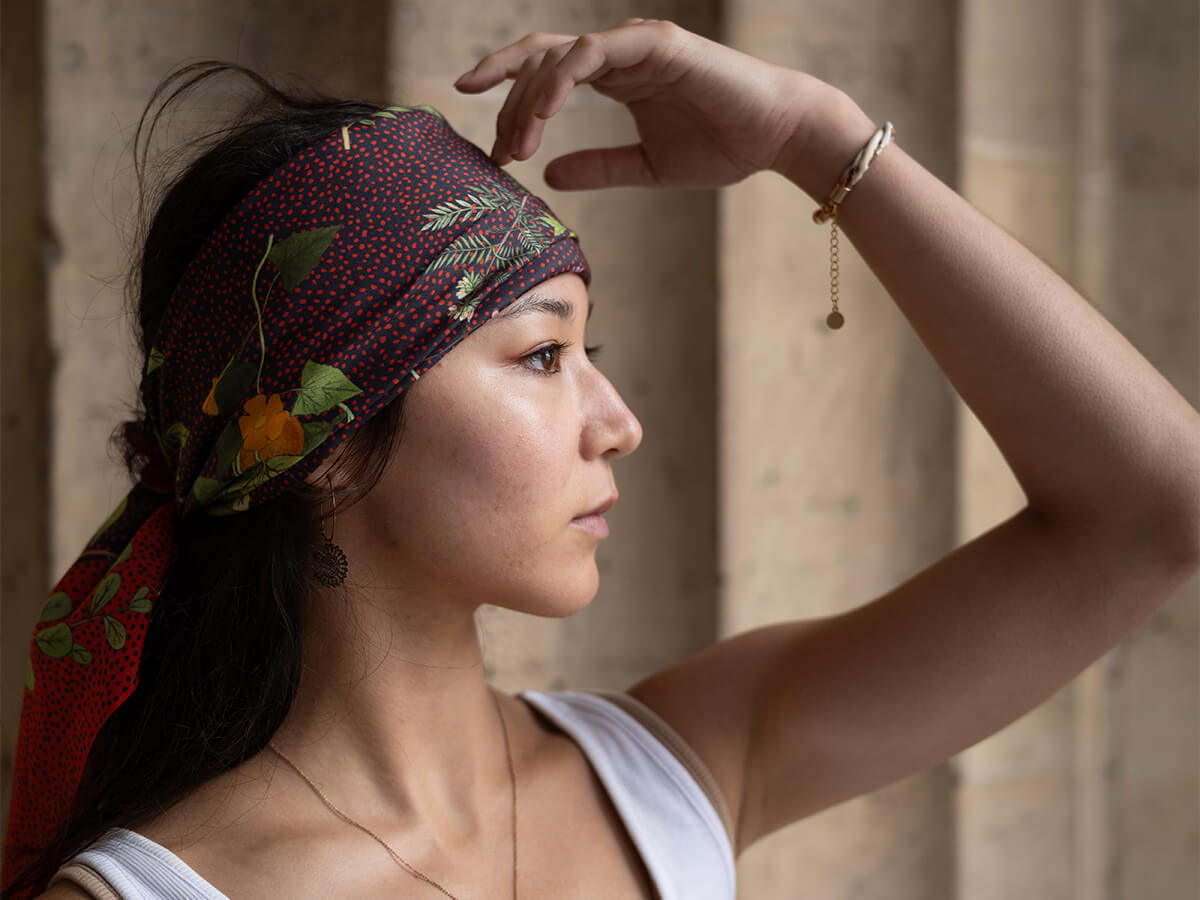 young lady wearing a black and red cotton silk scarf with flower motif and red dots around her head 