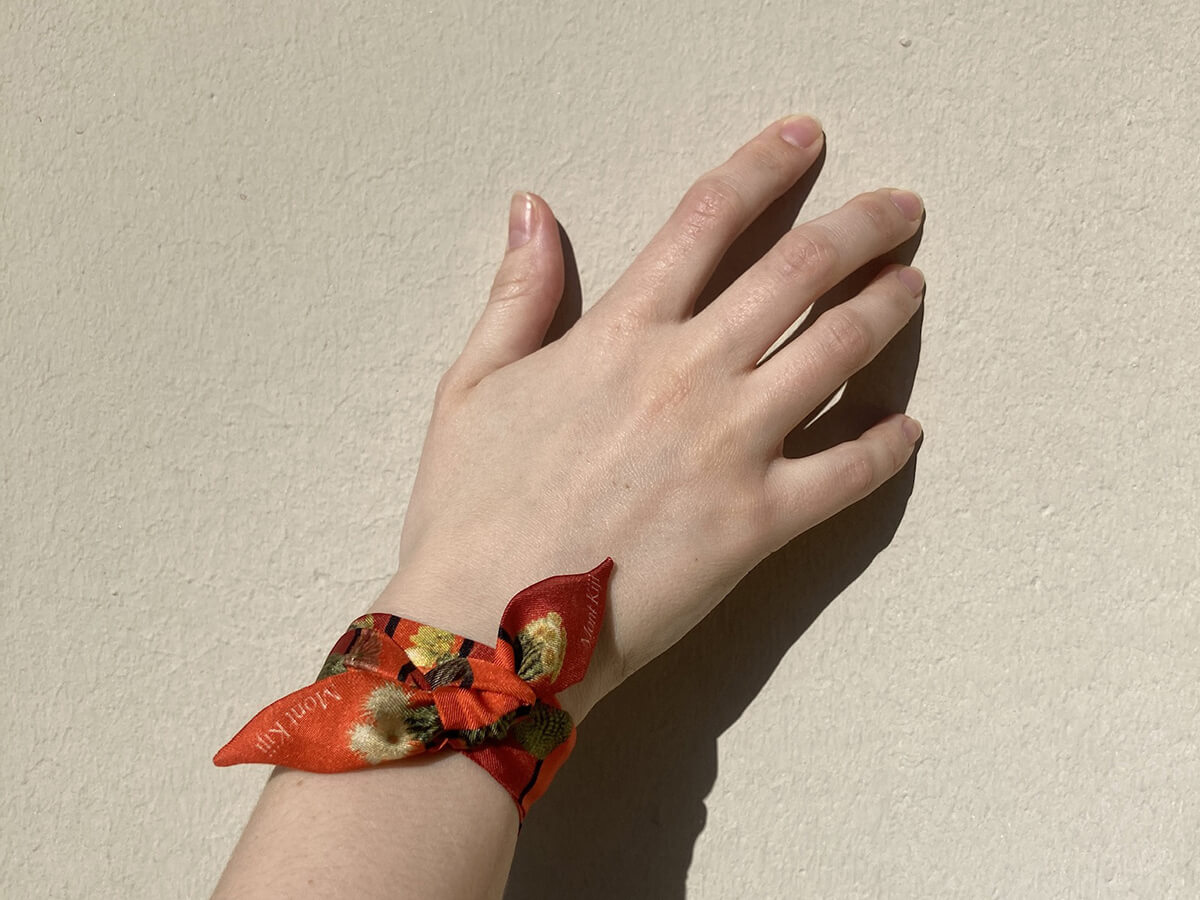 white hand with a red silk wristband with cactus motif around the wrist