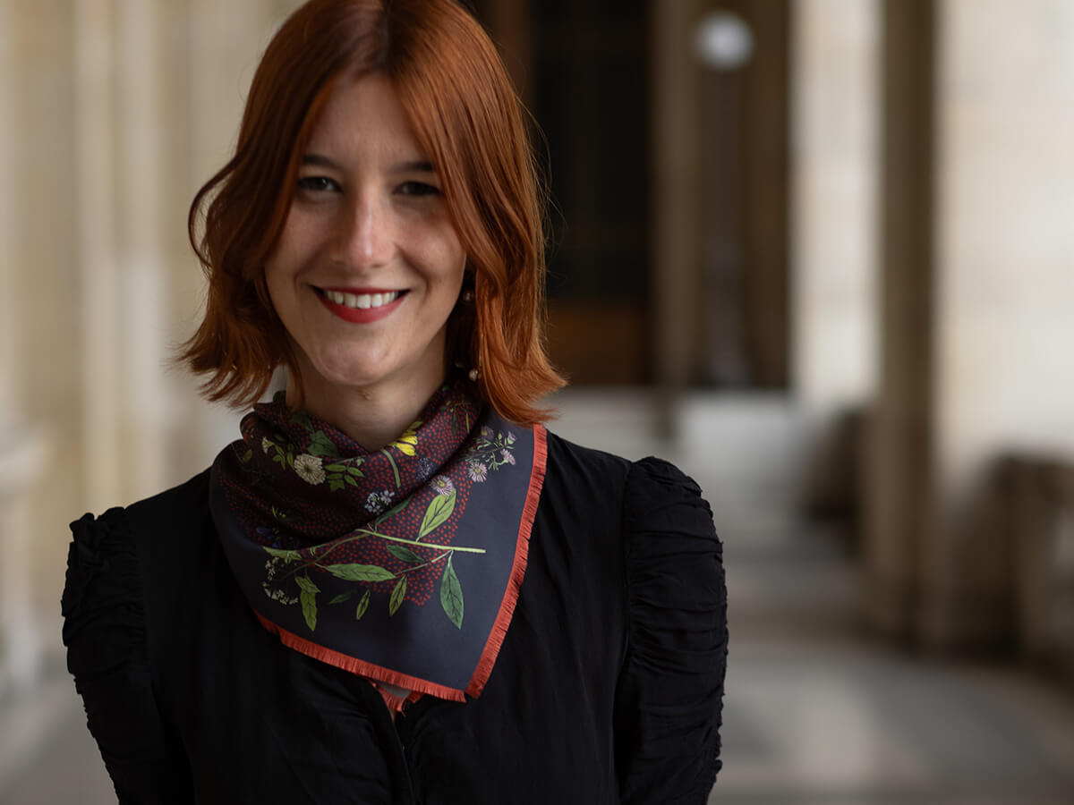 jeune femme portant un foulard en soie bleu-noir avec un motif mille-fleurs et un pull noir