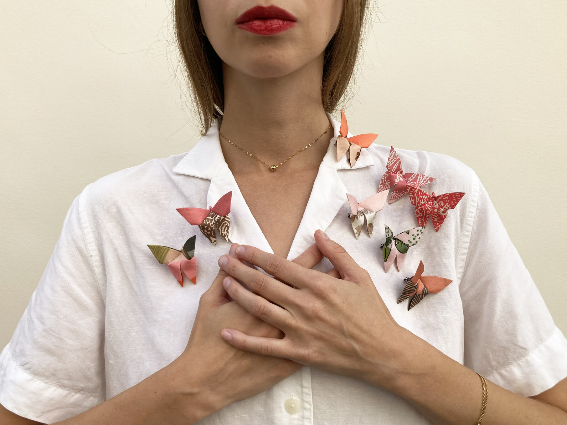 white woman wearing a white shirt with pink silk butterflies pinned over