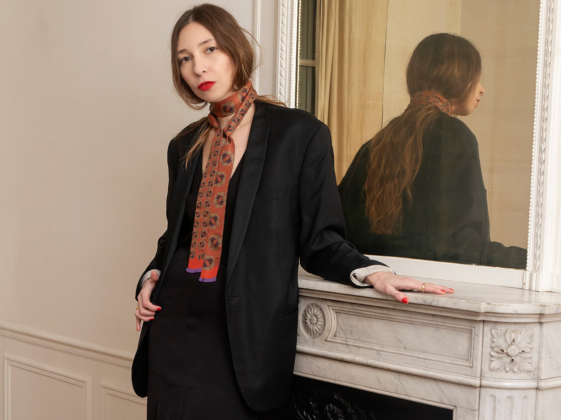 white woman wearing a red ling and skinny silk scarf with butterfly motif with a black jacket