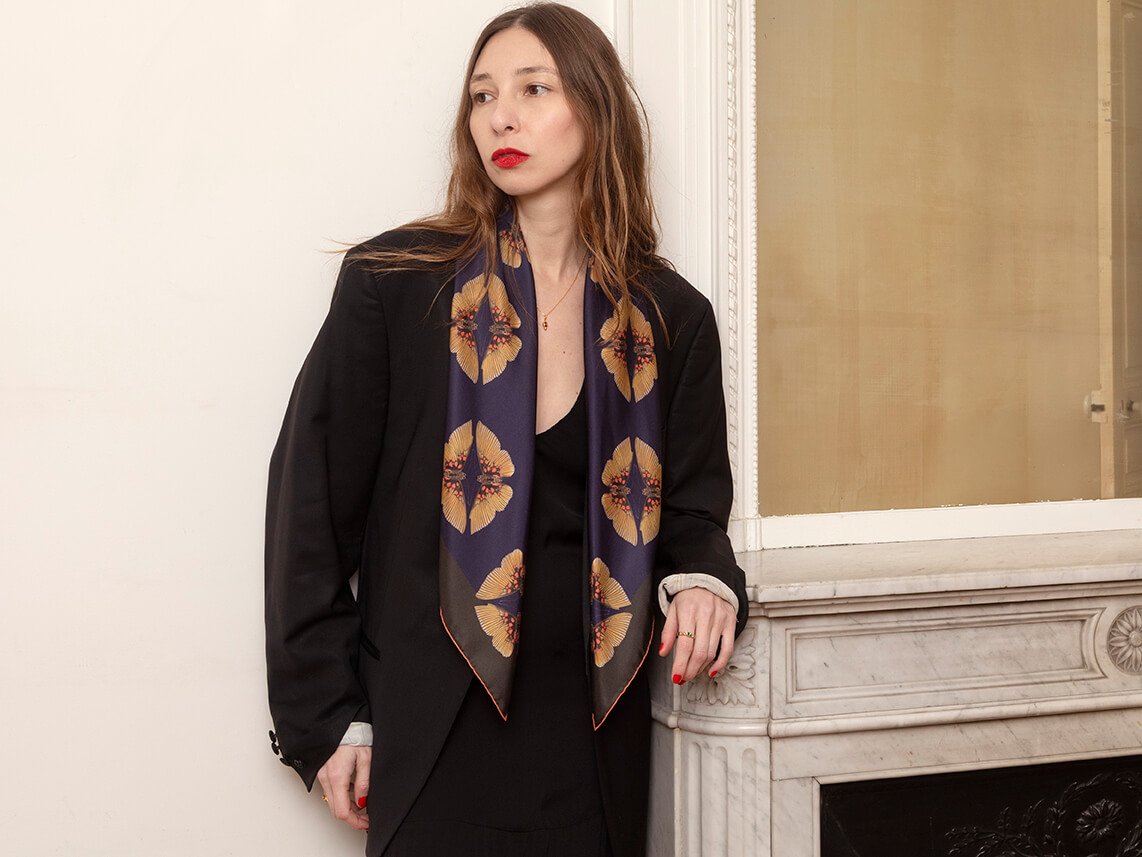 white woman wearing a black silk scarf with butterfly motif with a black jacket